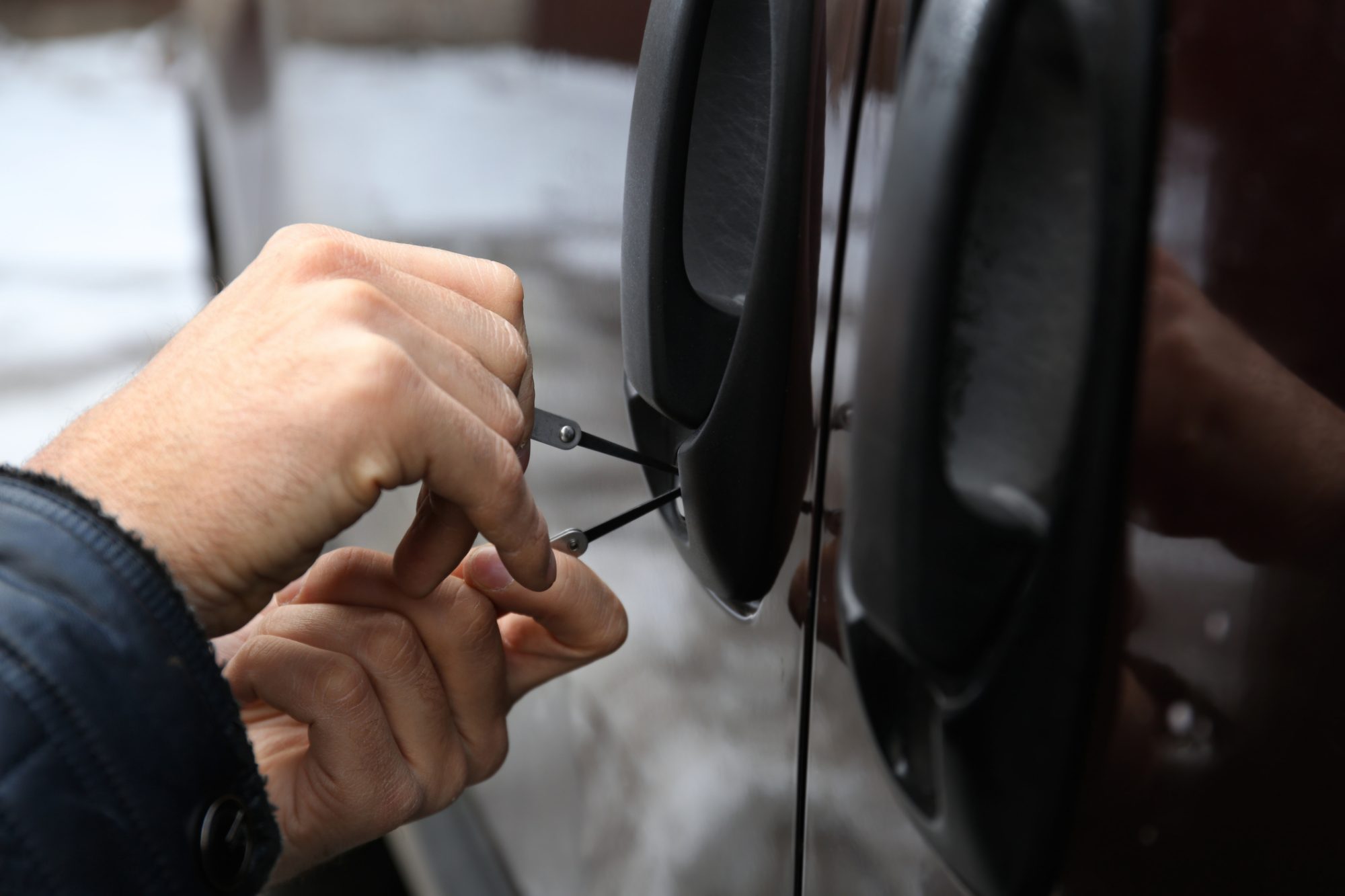 Closeup view of auto locksmith trying to open car with pick-lock